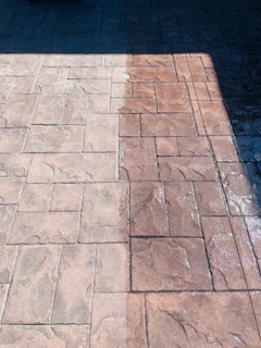 Patterned concrete patio or driveway with light and dark stone tiles before pressure washing cleaning service