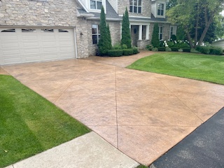 Large concrete driveway and patio freshly cleaned in Fond du Lac, Wisconsin residential area with green lawn and two-story home