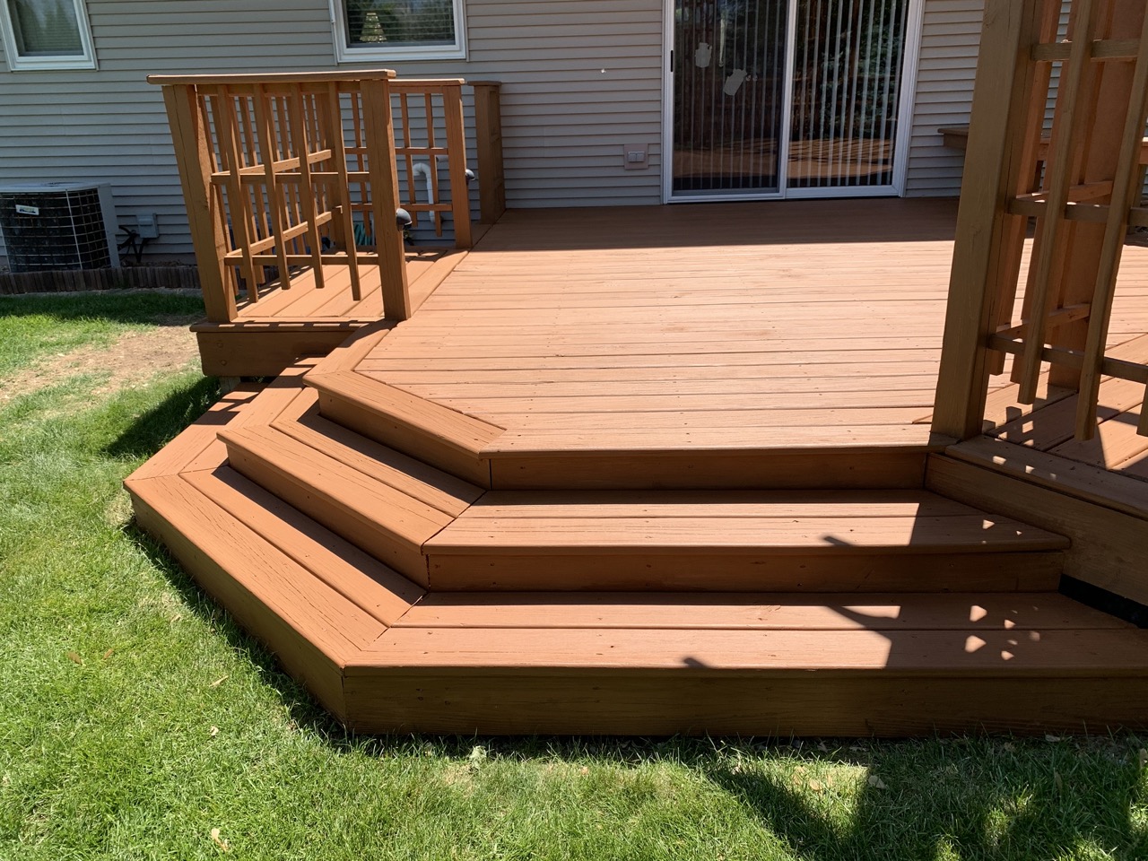 Composite deck with multiple levels and wooden stairs in Fond du Lac residential exterior, showing clean composite decking material and wooden railings