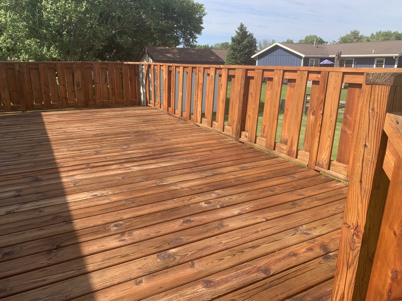 Newly pressure-washed wooden deck with railing in Fond du Lac, Wisconsin showing clean wood boards and fence panels after professional cleaning