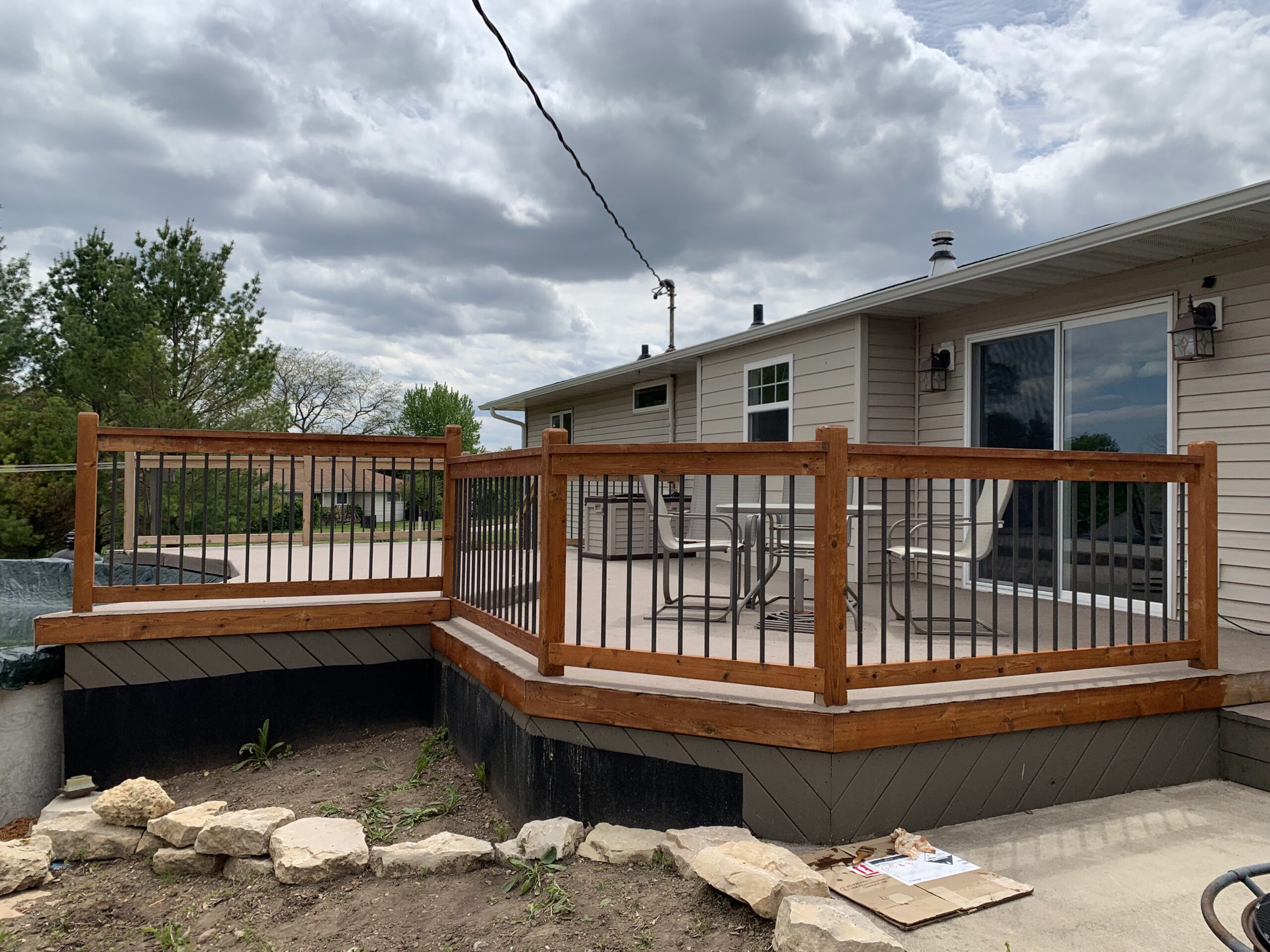 New wooden deck with metal railings attached to beige siding house in Fond du Lac, Wisconsin, showing deck cleaning and exterior house maintenance