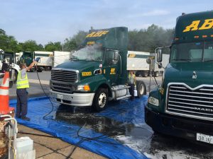 Fleet washing service in Fond du Lac, Wisconsin with commercial trucks lined up on blue containment mat for pressure washing and cleaning