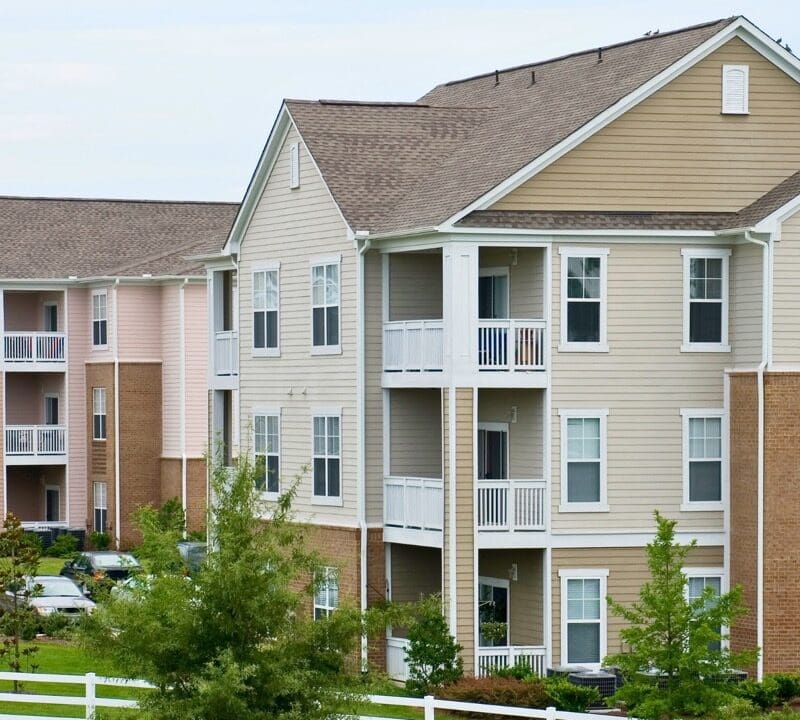 Row of three-story apartment buildings with brick and siding exteriors, white railings, and manicured landscaping in Fond du Lac, Wisconsin residential community