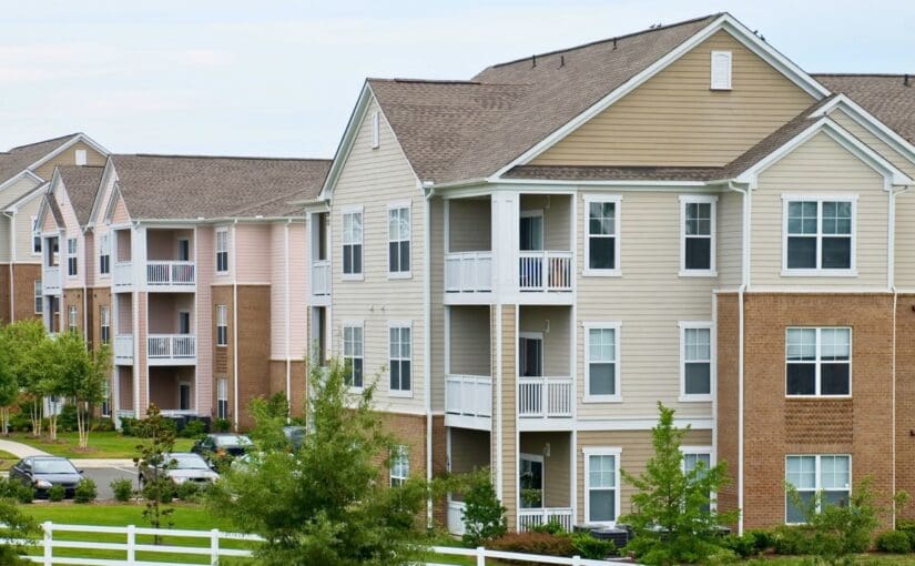 Row of three-story apartment buildings with brick and siding exteriors, white railings, and manicured landscaping in Fond du Lac, Wisconsin residential community