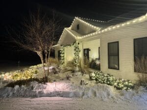 White house with holiday lights and snow-covered landscape at night in Fond du Lac, Wisconsin