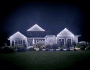 Modern two-story home at night with white exterior lighting outlining rooflines, landscaped foundation, and accent lighting highlighting architectural features in Fond du Lac, Wisconsin